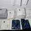 Stacks of folded shirts with a logo on a tiled wall background