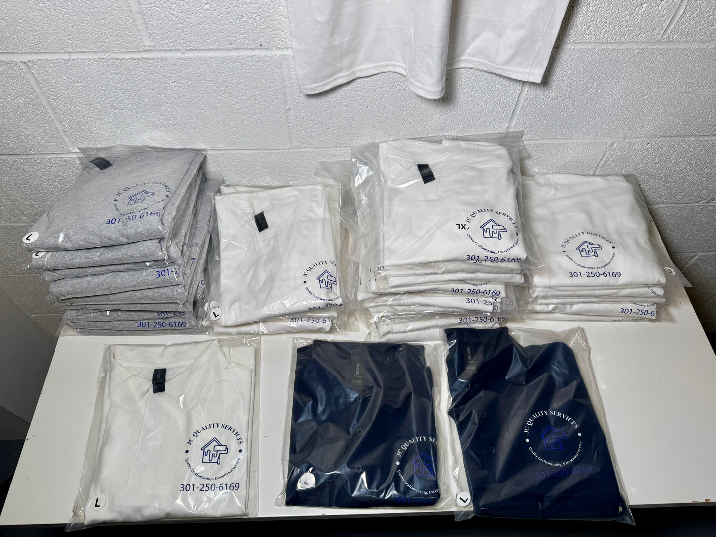 Stacks of folded shirts with a logo on a tiled wall background