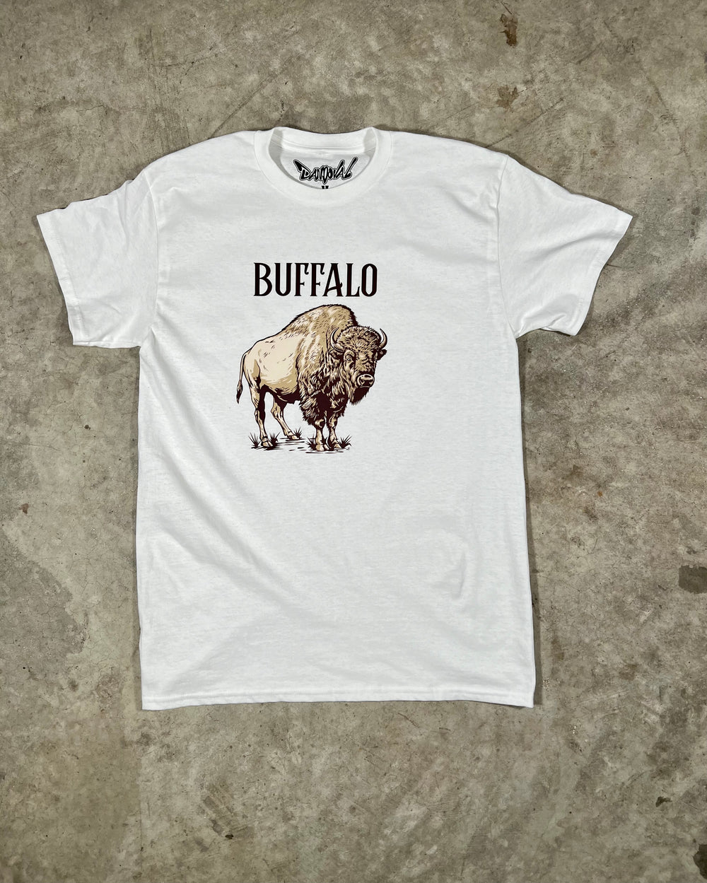 White t-shirt with a graphic of a buffalo and the word 'BUFFALO' on a concrete surface
