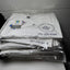 White t-shirts with logos and text on a shelf against a tiled wall.