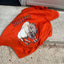 Red shirt with a graphic of a buffalo and the word 'Buffalo' on a concrete floor.
