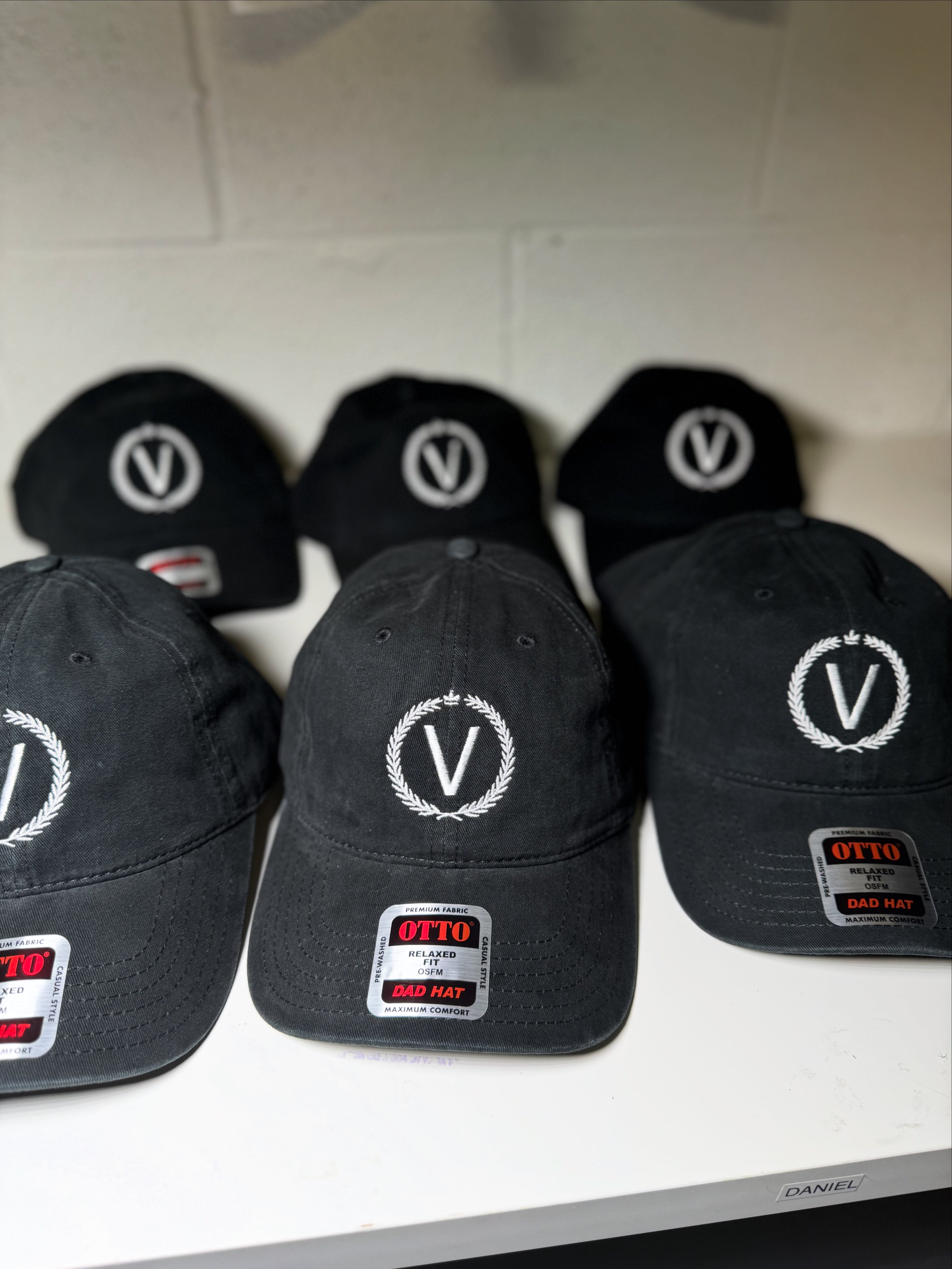 Black caps with a logo and brand name on a white surface