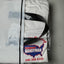 White t-shirt with red and blue graphics in a clear plastic bag on a gray background