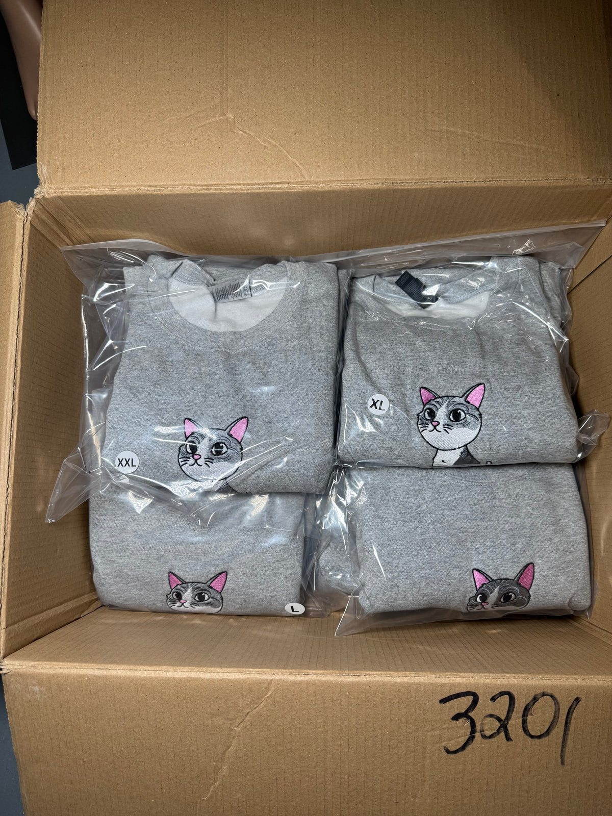 Gray sweatshirts with dog prints in a cardboard box