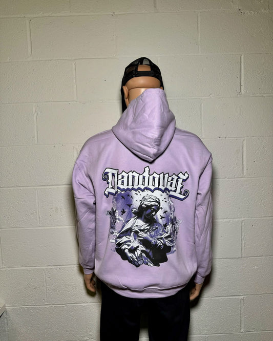 Person wearing a purple hoodie with a graphic design and text, standing against a white brick wall.