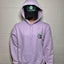 Person wearing a light purple hoodie with a logo, standing against a plain wall.