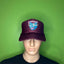 Mannequin head wearing a maroon cap with a logo against a green background