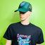 Mannequin wearing a black t-shirt with a colorful graphic design and a green cap on a green background