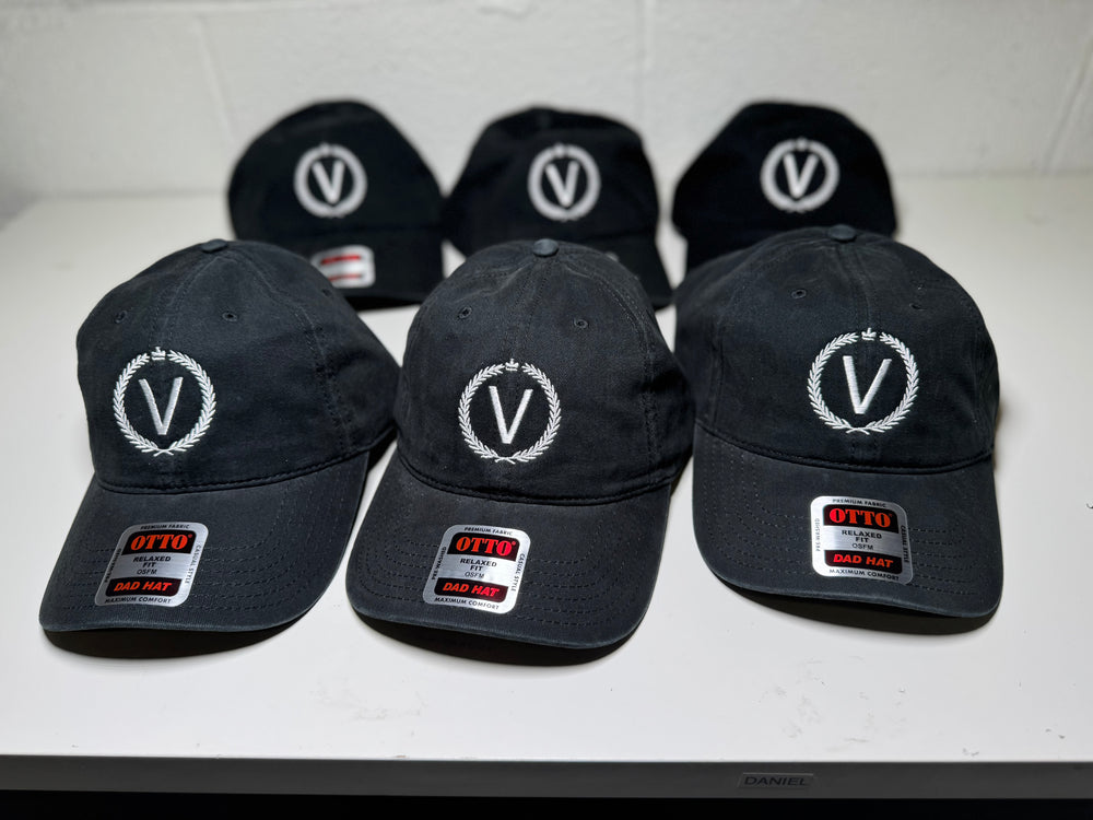 Black baseball caps with a logo and brand label on a white surface