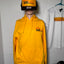 Mannequin wearing a yellow safety suit and helmet on a tiled floor.