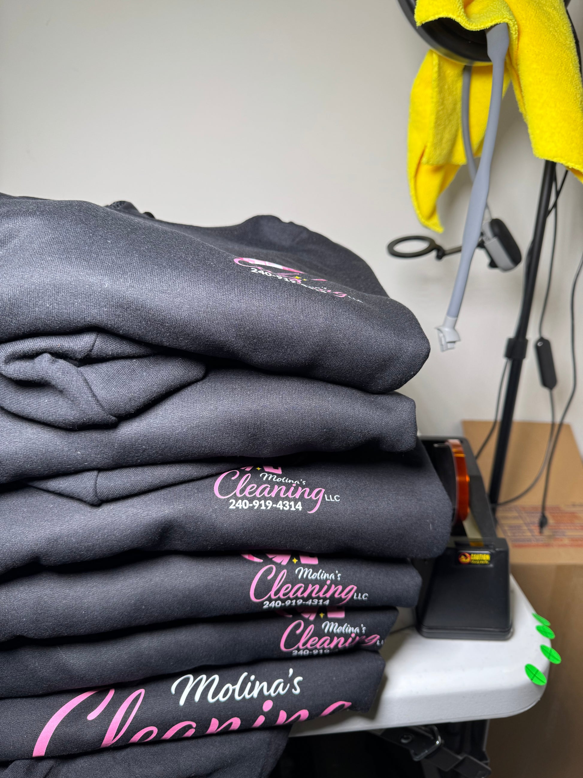Stack of gray hoodies with 'Maddox's Cleaning' logo on a white surface.