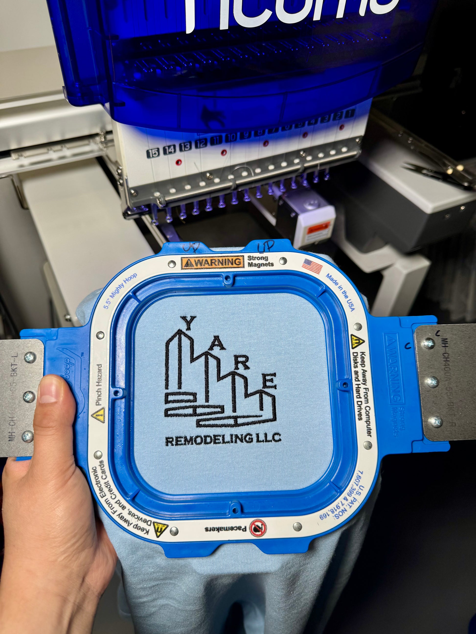 Blue toolbox with 'Yare Remodeling LLC' logo held by a hand, with a machine in the background.
