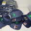 Stack of navy blue caps with green logos on a white surface