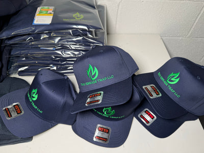 Stack of navy blue caps with green logos on a white surface