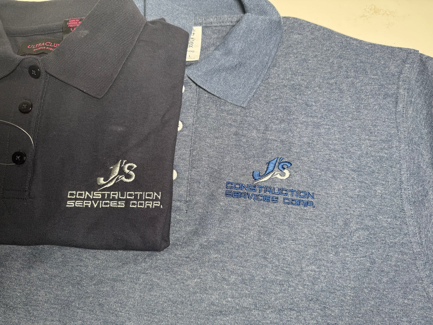 Two polo shirts with embroidered logos on a flat surface