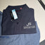 Folded navy blue shirt with a logo and tag on a gray surface