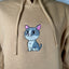 Beige hoodie with a cat patch on a plain background