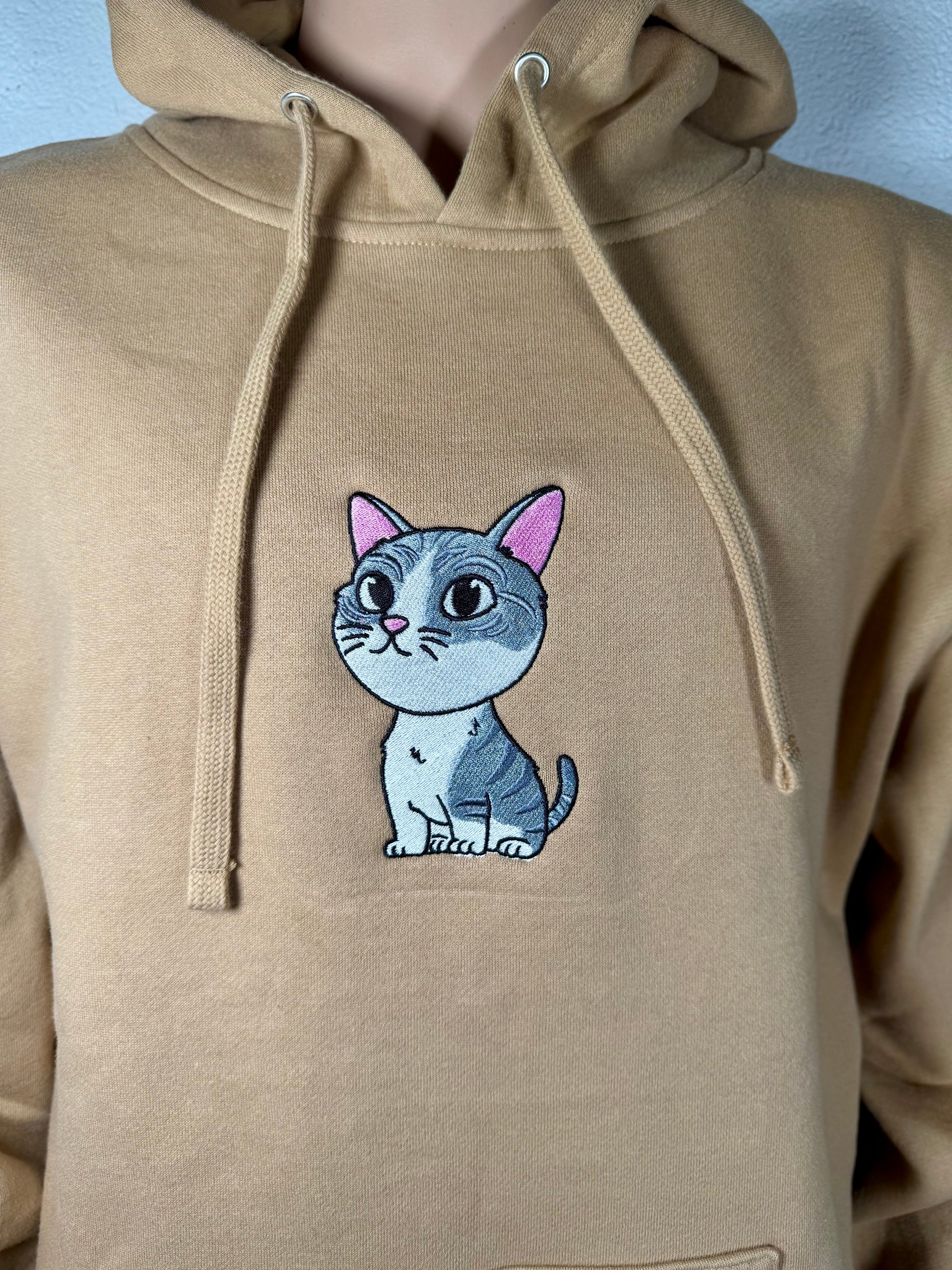 Beige hoodie with a cat patch on a plain background