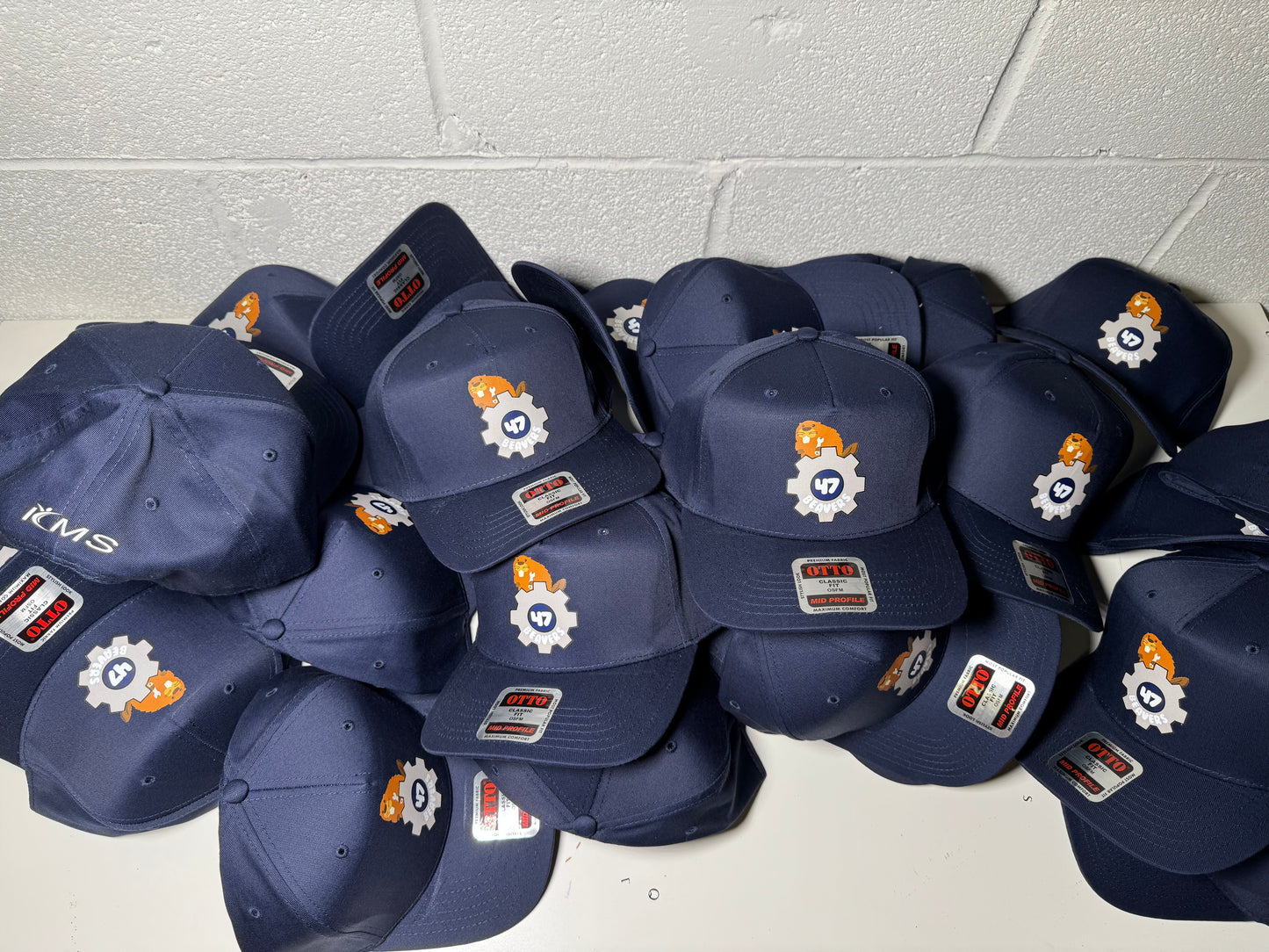 Stack of navy blue caps with logos on a white tiled floor